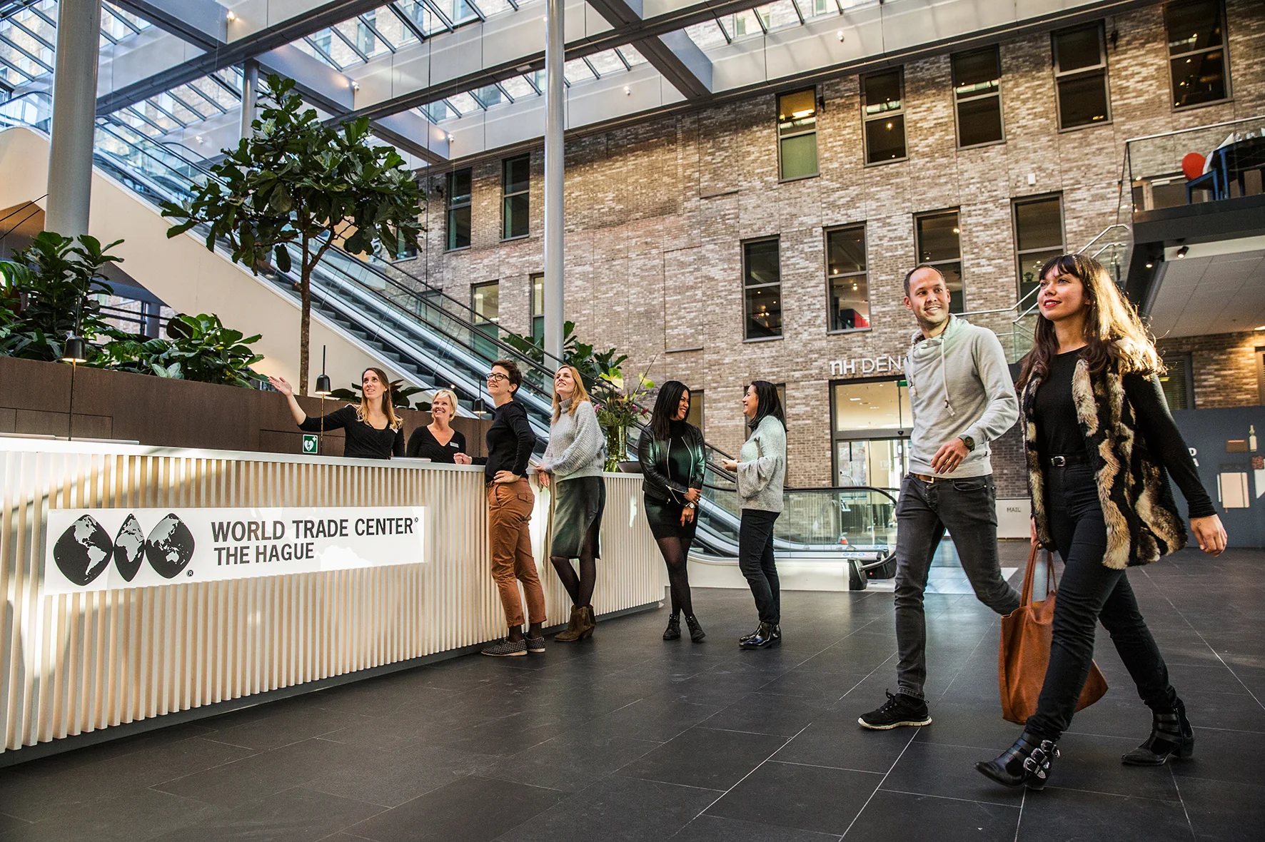 Mensen lopen en praten in de centrale hal van het World Trade Center The Hague aan de Prinses Beatrixlaan.
